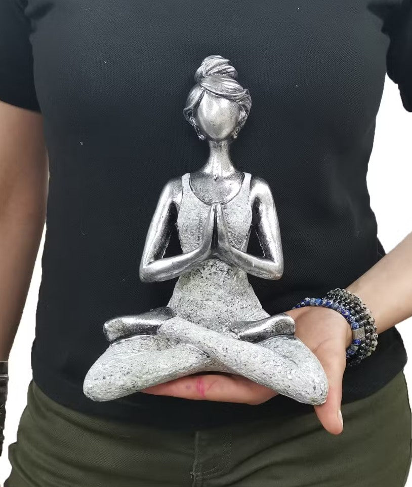 Person holding a silver yoga pose figurine against a black shirt background